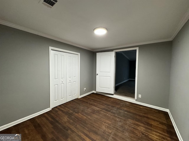 unfurnished bedroom with dark hardwood / wood-style flooring, ornamental molding, and a closet