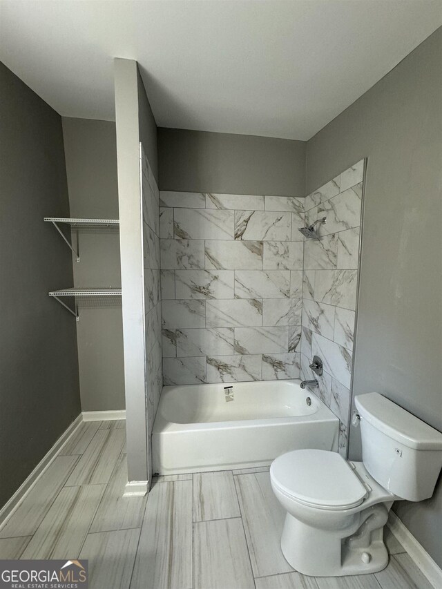 bathroom featuring toilet and tiled shower / bath