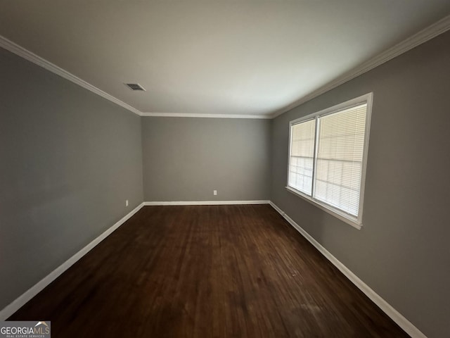 empty room featuring dark wood-type flooring and ornamental molding