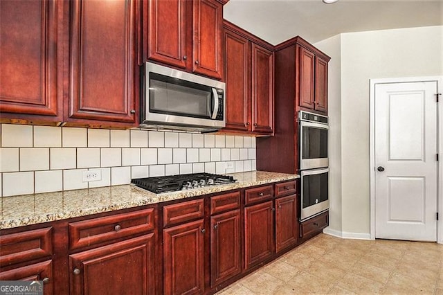 kitchen with backsplash, light stone counters, stainless steel appliances, and light tile floors