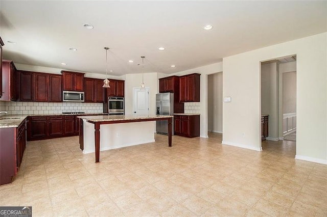 kitchen with appliances with stainless steel finishes, light stone counters, a kitchen island, tasteful backsplash, and pendant lighting