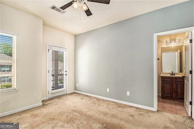 carpeted empty room featuring sink, ceiling fan, and a healthy amount of sunlight