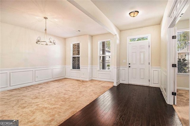 foyer with carpet and a notable chandelier