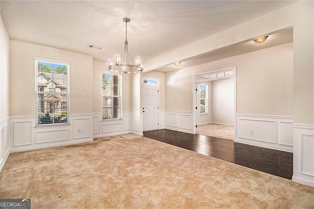 unfurnished room with carpet and a notable chandelier