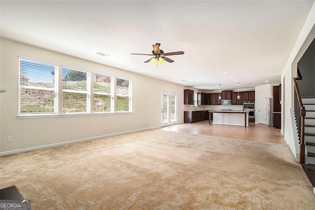 unfurnished living room with plenty of natural light, light carpet, and ceiling fan