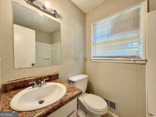 bathroom featuring vanity, toilet, and a textured ceiling