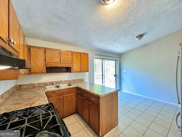 kitchen with appliances with stainless steel finishes, sink, kitchen peninsula, light tile patterned floors, and a textured ceiling