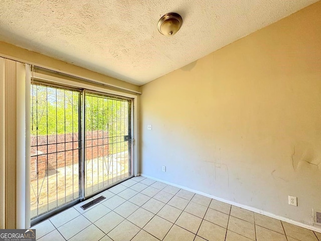 spare room featuring light tile patterned floors and a textured ceiling