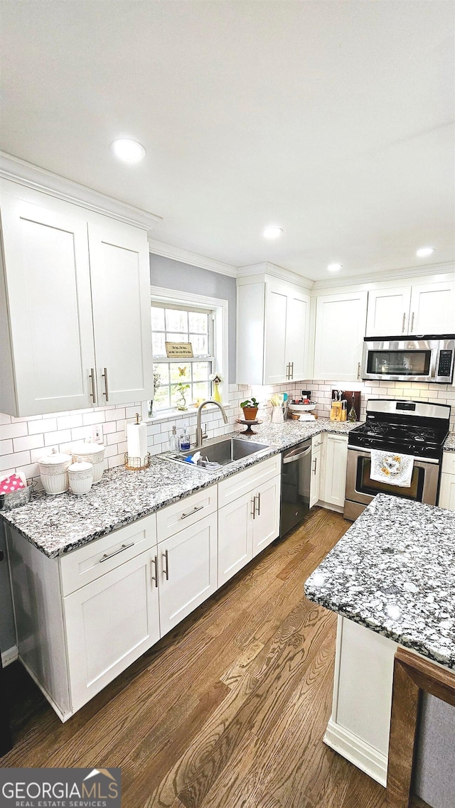 kitchen featuring sink, dark wood-type flooring, white cabinetry, stainless steel appliances, and light stone countertops