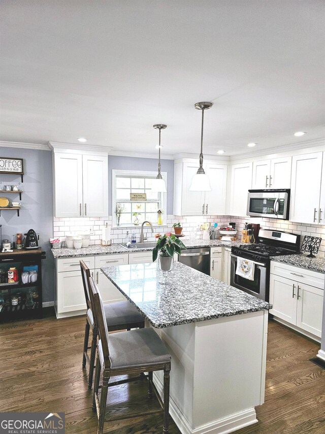 kitchen featuring pendant lighting, dark wood-type flooring, white cabinetry, appliances with stainless steel finishes, and a center island