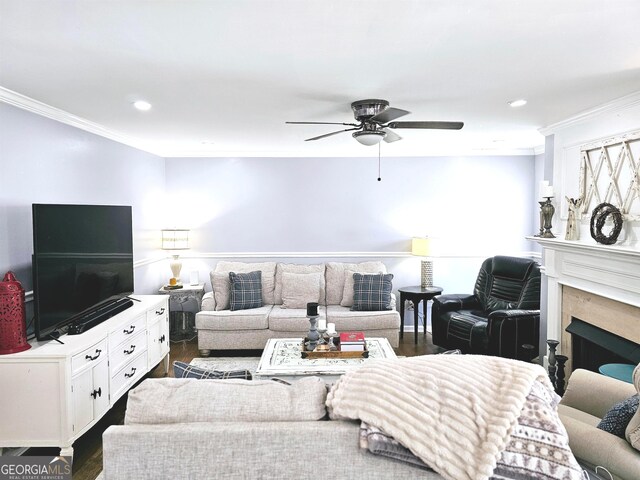 living room featuring ceiling fan, a premium fireplace, dark hardwood / wood-style flooring, and crown molding