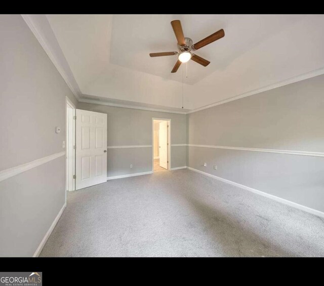 spare room with a raised ceiling, carpet flooring, ornamental molding, and ceiling fan