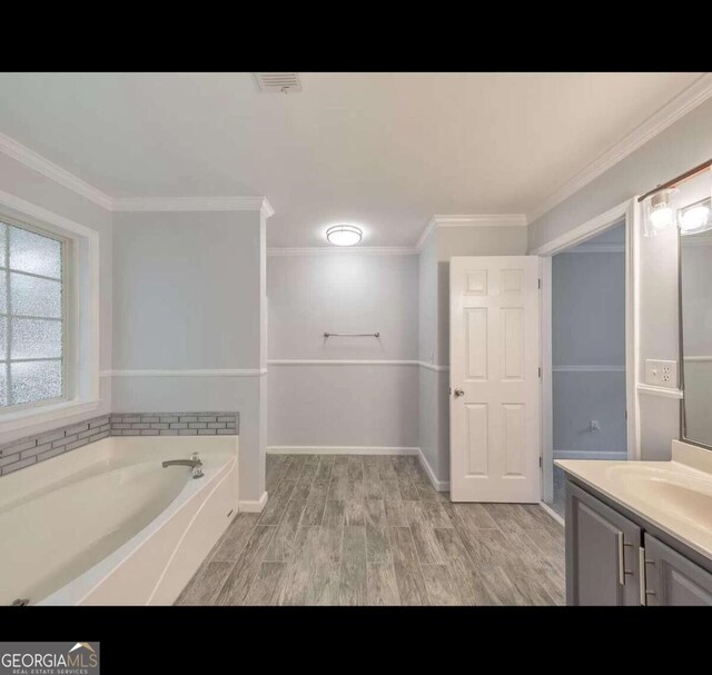 bathroom featuring a bathtub, ornamental molding, vanity, and hardwood / wood-style floors