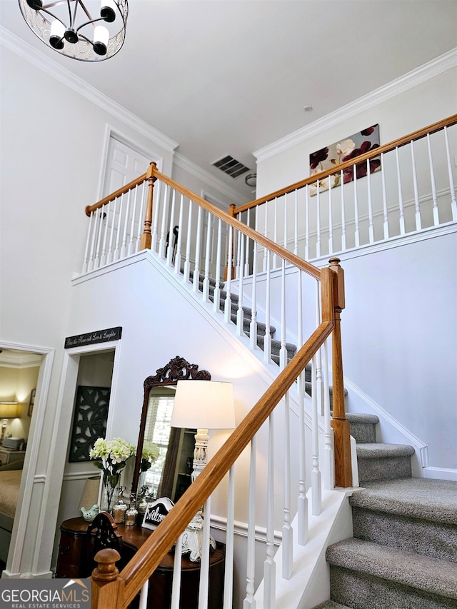 staircase featuring ornamental molding and a notable chandelier