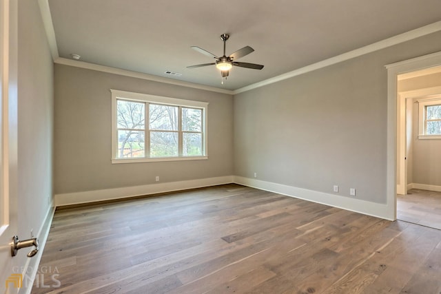 spare room with ceiling fan, ornamental molding, a wealth of natural light, and hardwood / wood-style floors