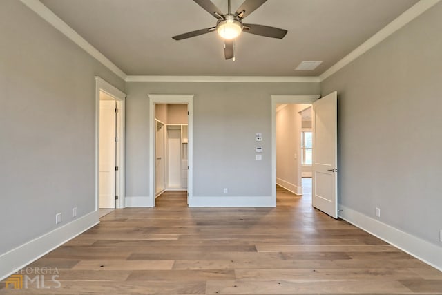 unfurnished bedroom featuring ornamental molding, wood-type flooring, and a walk in closet