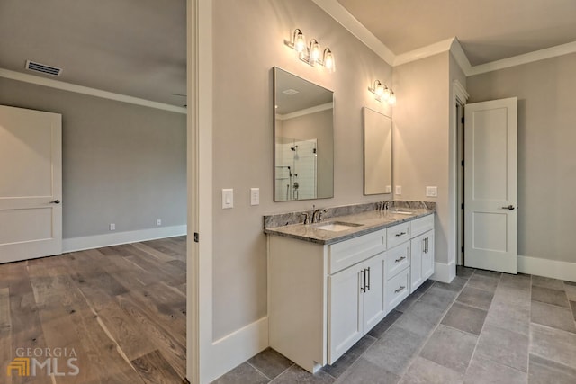 bathroom with ornamental molding, dual bowl vanity, and hardwood / wood-style floors