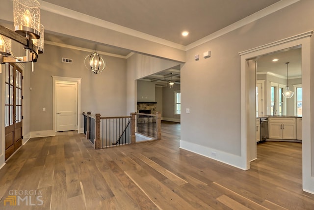 empty room featuring ornamental molding, dark wood-type flooring, a fireplace, and ceiling fan with notable chandelier