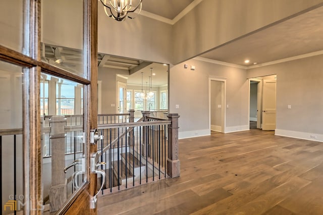 foyer entrance featuring crown molding, dark wood-type flooring, and a chandelier