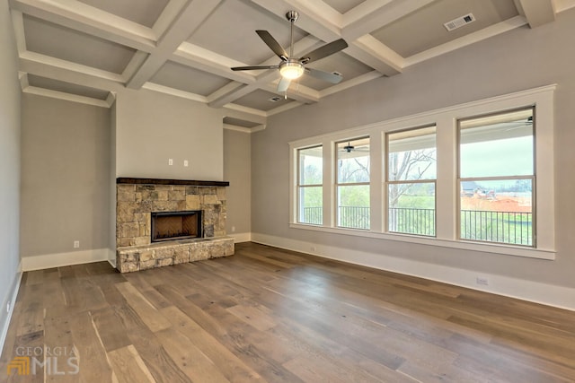 unfurnished living room with a stone fireplace, coffered ceiling, ceiling fan, beamed ceiling, and dark hardwood / wood-style floors