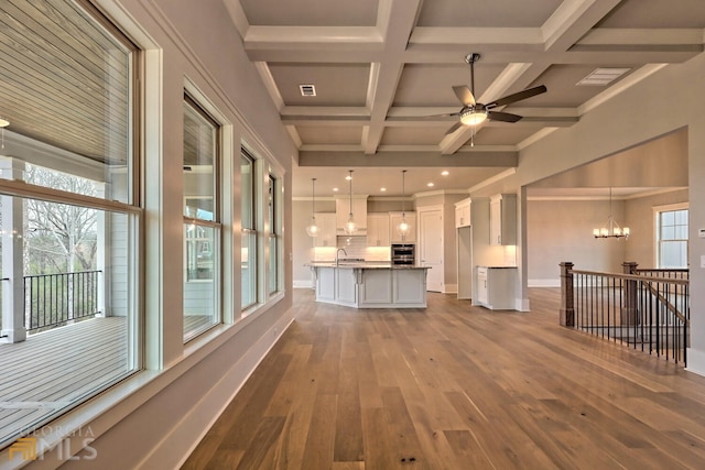 unfurnished living room featuring coffered ceiling, light hardwood / wood-style flooring, a wealth of natural light, and beam ceiling