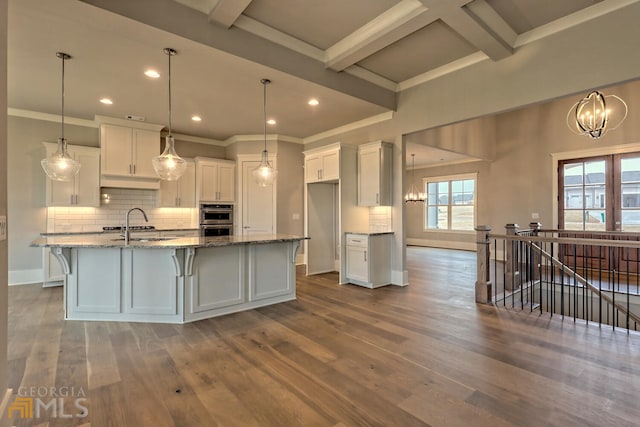 kitchen featuring an inviting chandelier, beam ceiling, white cabinetry, and wood-type flooring