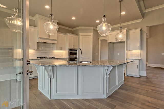 kitchen featuring tasteful backsplash, white cabinets, hardwood / wood-style flooring, and decorative light fixtures