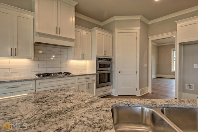 kitchen with light hardwood / wood-style floors, tasteful backsplash, white cabinetry, stainless steel appliances, and light stone countertops