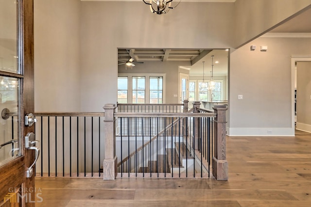 hall featuring ornamental molding, wood-type flooring, and a chandelier