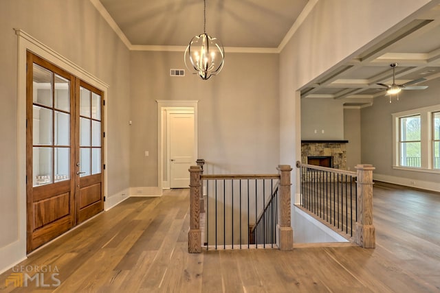 foyer featuring dark hardwood / wood-style flooring, french doors, ceiling fan with notable chandelier, and coffered ceiling