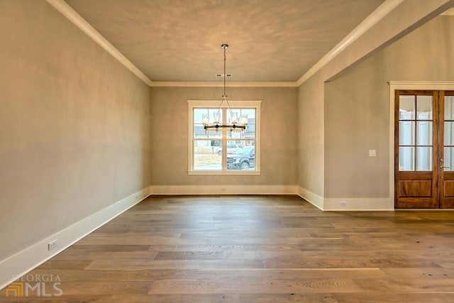 unfurnished room featuring crown molding, dark wood-type flooring, a chandelier, and french doors