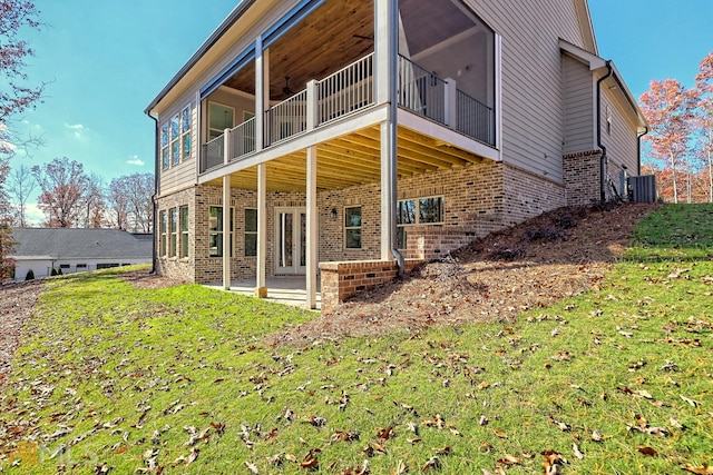 rear view of house with central AC unit, a balcony, a patio area, and a yard