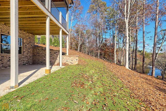 view of yard featuring a water view, a balcony, and a patio area