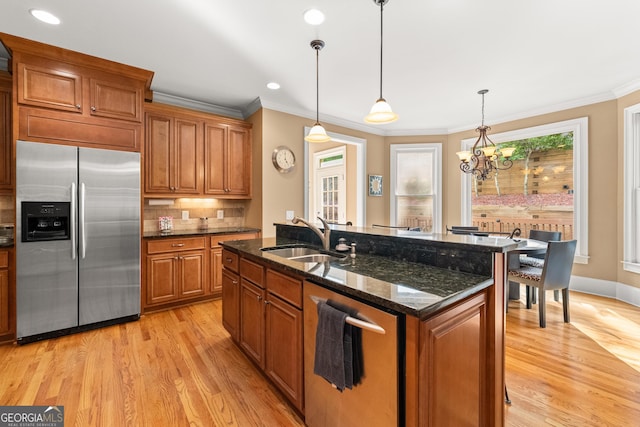 kitchen with stainless steel appliances, sink, decorative light fixtures, a notable chandelier, and an island with sink