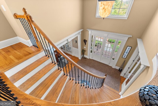 stairs featuring hardwood / wood-style flooring, a high ceiling, and a wealth of natural light