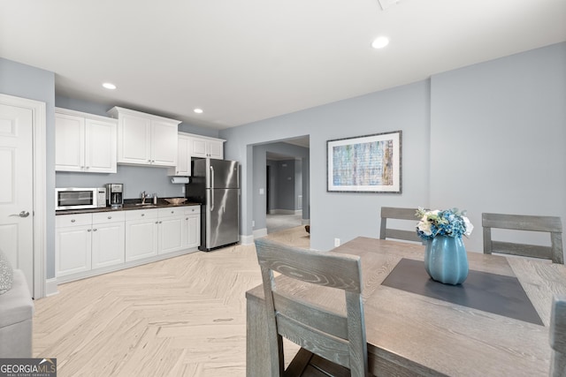 kitchen featuring light parquet flooring, stainless steel appliances, and white cabinetry