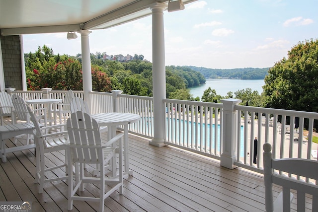 wooden terrace with a water view and a fenced in pool