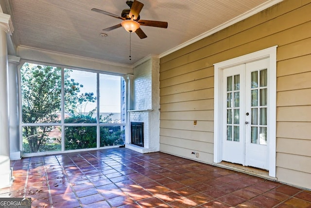 unfurnished sunroom with french doors, a fireplace, a healthy amount of sunlight, and ceiling fan