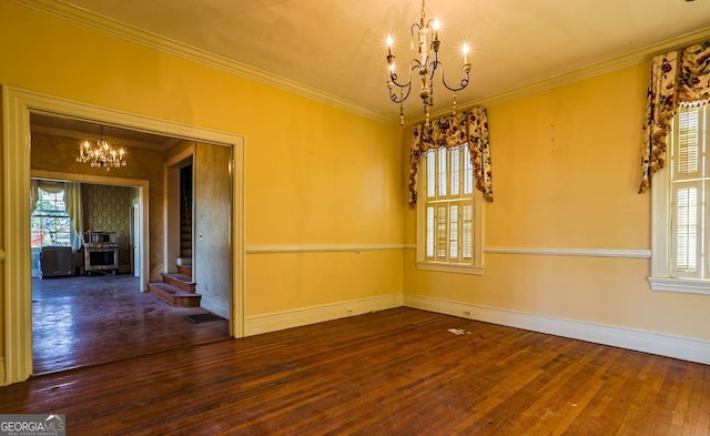 spare room featuring dark hardwood / wood-style flooring, crown molding, and an inviting chandelier