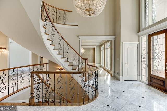 tiled entrance foyer featuring a high ceiling and a chandelier