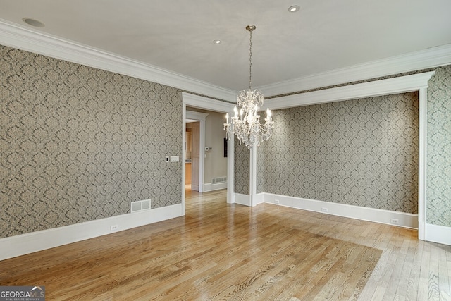 unfurnished room featuring a chandelier, light hardwood / wood-style floors, and crown molding