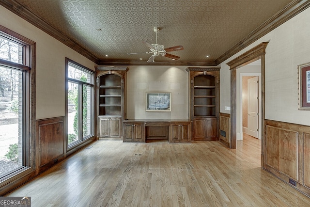 unfurnished office featuring plenty of natural light, ceiling fan, light wood-type flooring, and crown molding