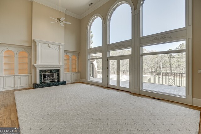 unfurnished living room with a high end fireplace, plenty of natural light, and ceiling fan