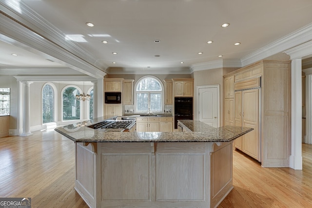 kitchen with crown molding, light hardwood / wood-style floors, a center island, and black appliances