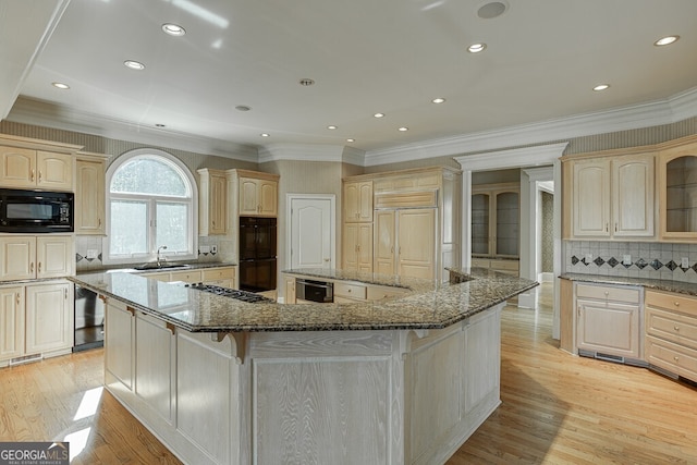 kitchen with tasteful backsplash, light hardwood / wood-style floors, a kitchen island, and black appliances