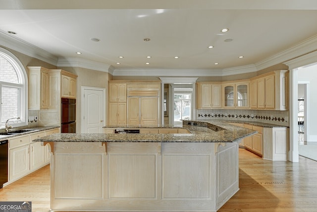 kitchen with sink, dark stone countertops, backsplash, and a kitchen island