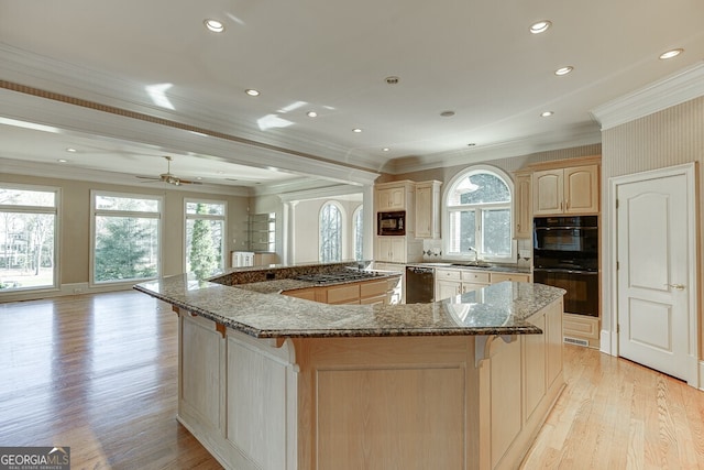 kitchen featuring black appliances, crown molding, a kitchen island, and light hardwood / wood-style floors