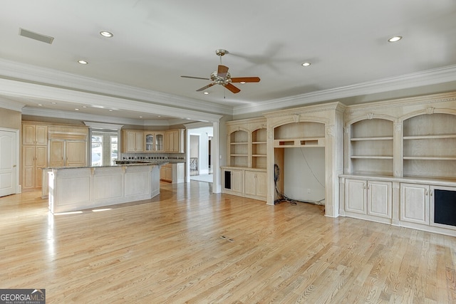 unfurnished living room with crown molding, ceiling fan, built in shelves, and light hardwood / wood-style flooring