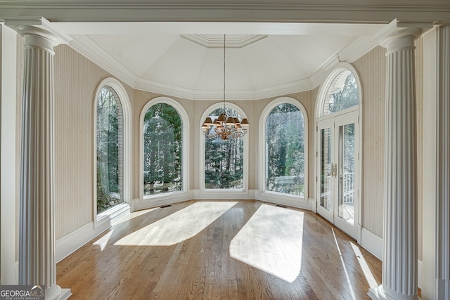 unfurnished sunroom with lofted ceiling, a chandelier, and ornate columns