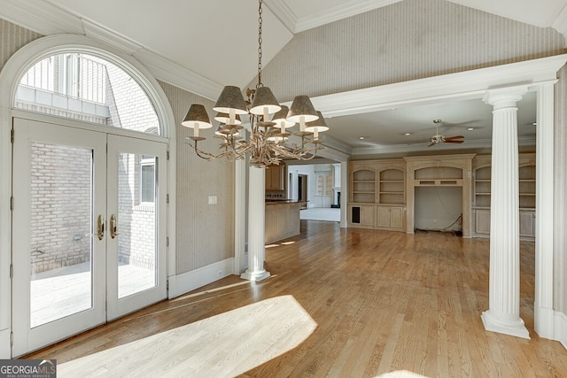 interior space with french doors, ornamental molding, ornate columns, ceiling fan with notable chandelier, and light wood-type flooring